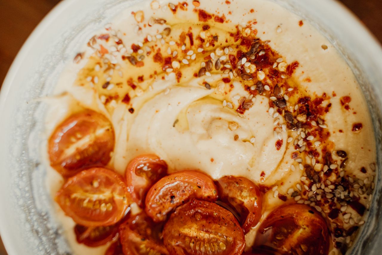 Services Delicious spiced hummus topped with roasted cherry tomatoes and sesame seeds.