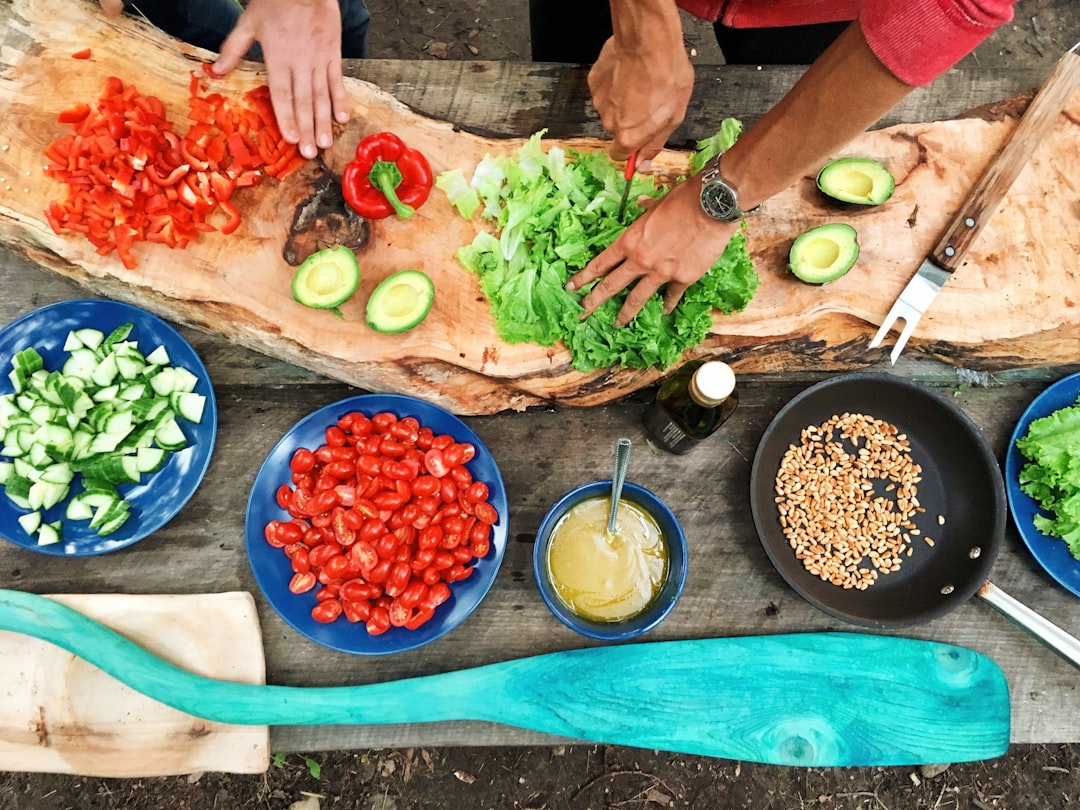 About person-slicing-green-vegetable-in-front-of-round-ceramic-plates-with-assorted-sliced-vegetables-during-daytime-ezh46xcdqry